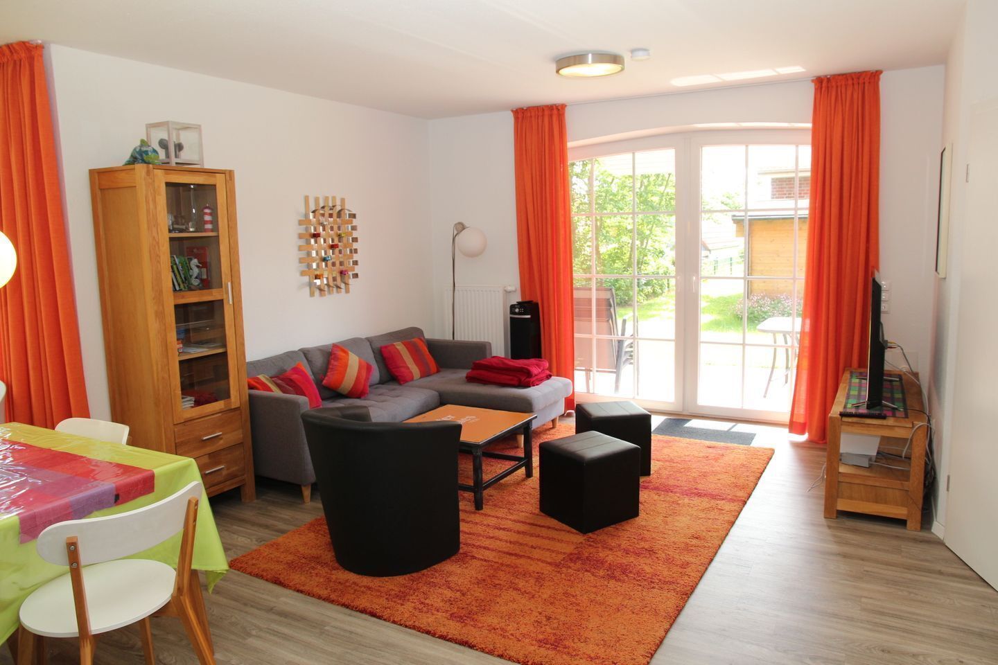 Een woonkamer met een bank, poefjes, een salontafel, een houten kast en een tv-meubel.