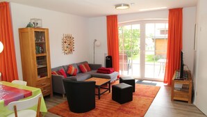 A living room with a sofa, ottomans, a coffee table, a wooden cabinet, and a TV stand.