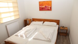 A neatly made bed with white linens, a wooden headboard, and a bedside table with a lamp.