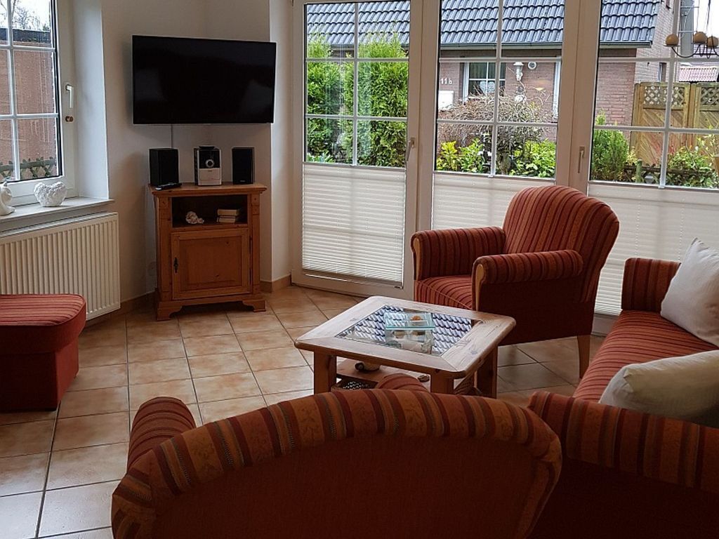 Una sala de estar con televisor, parlantes y una mesa de centro de vidrio.