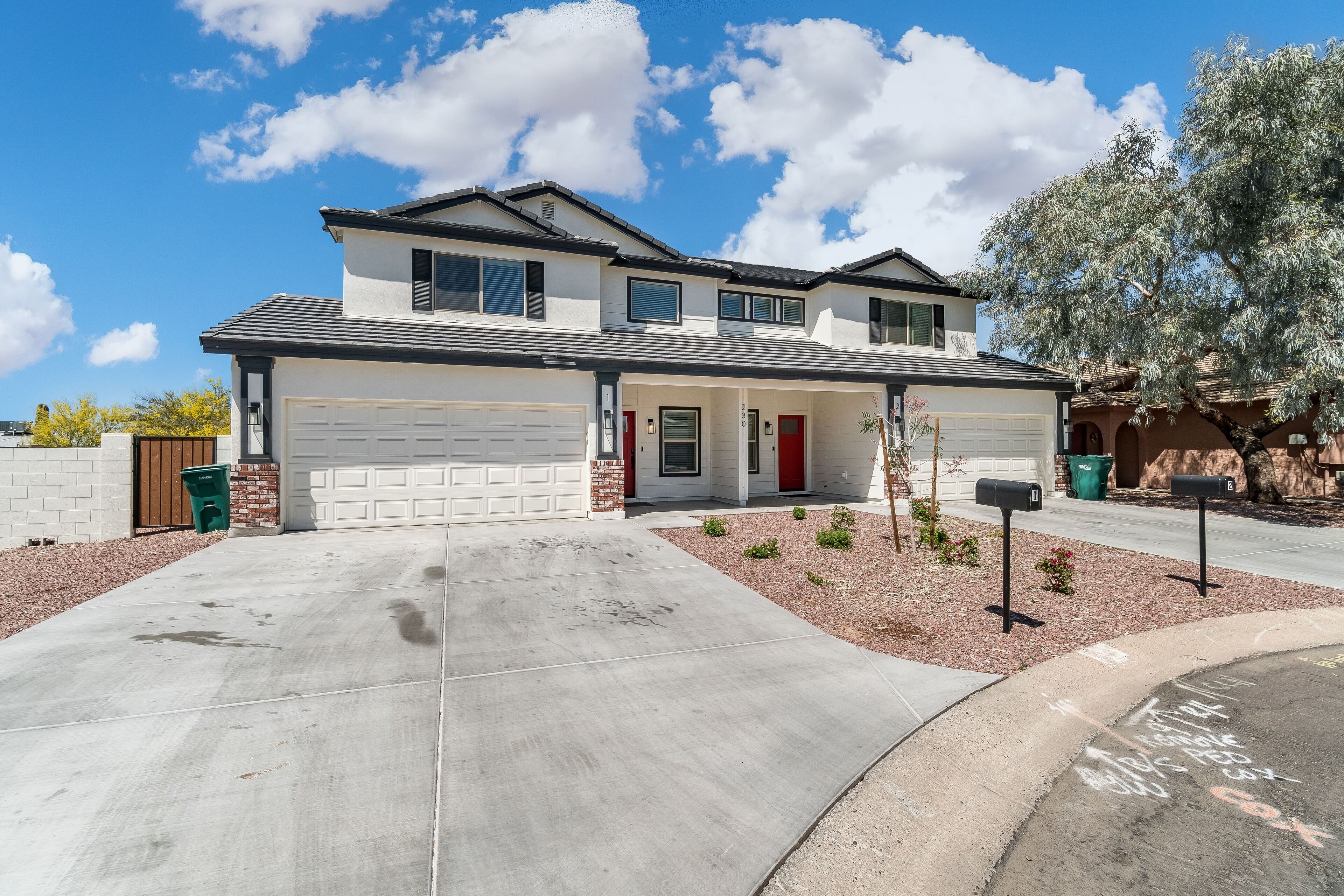 A two-story house with a garage, a red door, and a driveway leading to the garage.