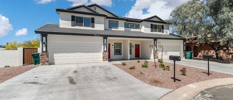 A two-story house with a garage, a red door, and a driveway leading to the garage.