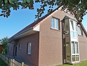 Ein zweistöckiges Ziegelhaus mit Veranda, Erkerfenster und einer Tür zu einer überdachten Veranda.