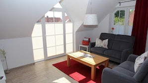A modern living room with a grey sofa, a wooden coffee table, and a red rug.