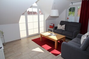 A modern living room with a grey sofa, a wooden coffee table, and a red rug.