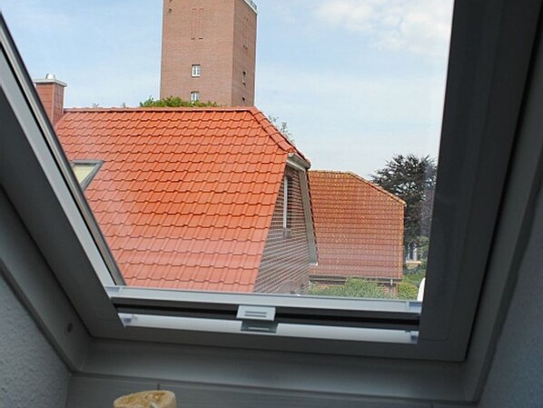 A skylight with a view of a red-tiled roof and a brick chimney.