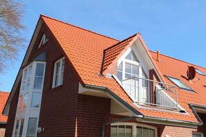 Ein zweistöckiges Haus mit roten Ziegeln, einem sichtbaren Schornstein und einer Satellitenschüssel.