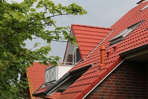 Ein rotes Ziegeldach mit einem Dachfenster und einem Schornstein.