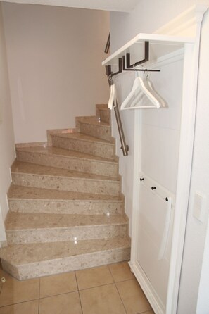 A staircase with beige steps and a white door at the bottom. - Doris - Great top floor apartment (75sqm) for 4 people with guest WC and balcony (Krummhörn)