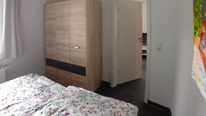 A bedroom with a bed, a wardrobe, and a door leading to another room.