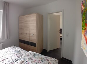 Une chambre à coucher comprenant un lit, une armoire et une porte donnant sur une autre pièce.