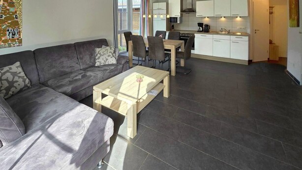 A modern living room with a sofa, coffee table, and dining area with chairs.
