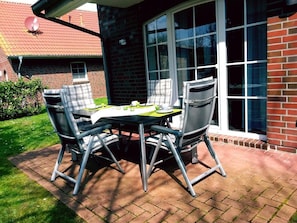 Un patio con mesa y sillas, un muro de ladrillo y una ventana.