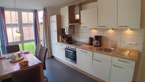 A modern kitchen with white cabinets, a built-in oven, a coffee maker, and a sink.