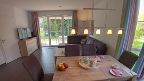A dining area with a wooden table, chairs, and a view through large windows.