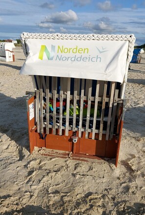 Eine Holzkonstruktion am Strand mit weißem Baldachin, beschriftet mit 'Norden Niedersachsen'.