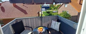 Ein Balkon mit Tisch, Stühlen und einer kleinen Anrichte mit Obst.