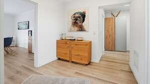 A hallway with a wooden dresser, a painting, and a wooden door. - Strandfloh - Gemütliche Ferienwohnung mit Fahrstuhl (Norden)