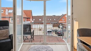 A balcony with a view of a residential area, a table, and chairs. - Strandfloh - Gemütliche Ferienwohnung mit Fahrstuhl (Norden)