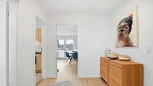 A hallway with a wooden cabinet, a rug, and a painting on the wall. - Strandfloh - Gemütliche Ferienwohnung mit Fahrstuhl (Norden)