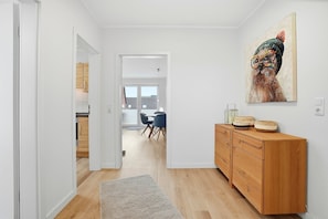 A hallway with a wooden cabinet, a rug, and a painting on the wall.
