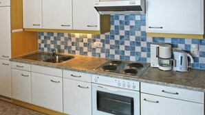 A compact kitchen with white cabinets, a gas stove, a coffee maker, and a microwave. - Cosy apartment for 13 guests with WIFI, TV and balcony (See)
