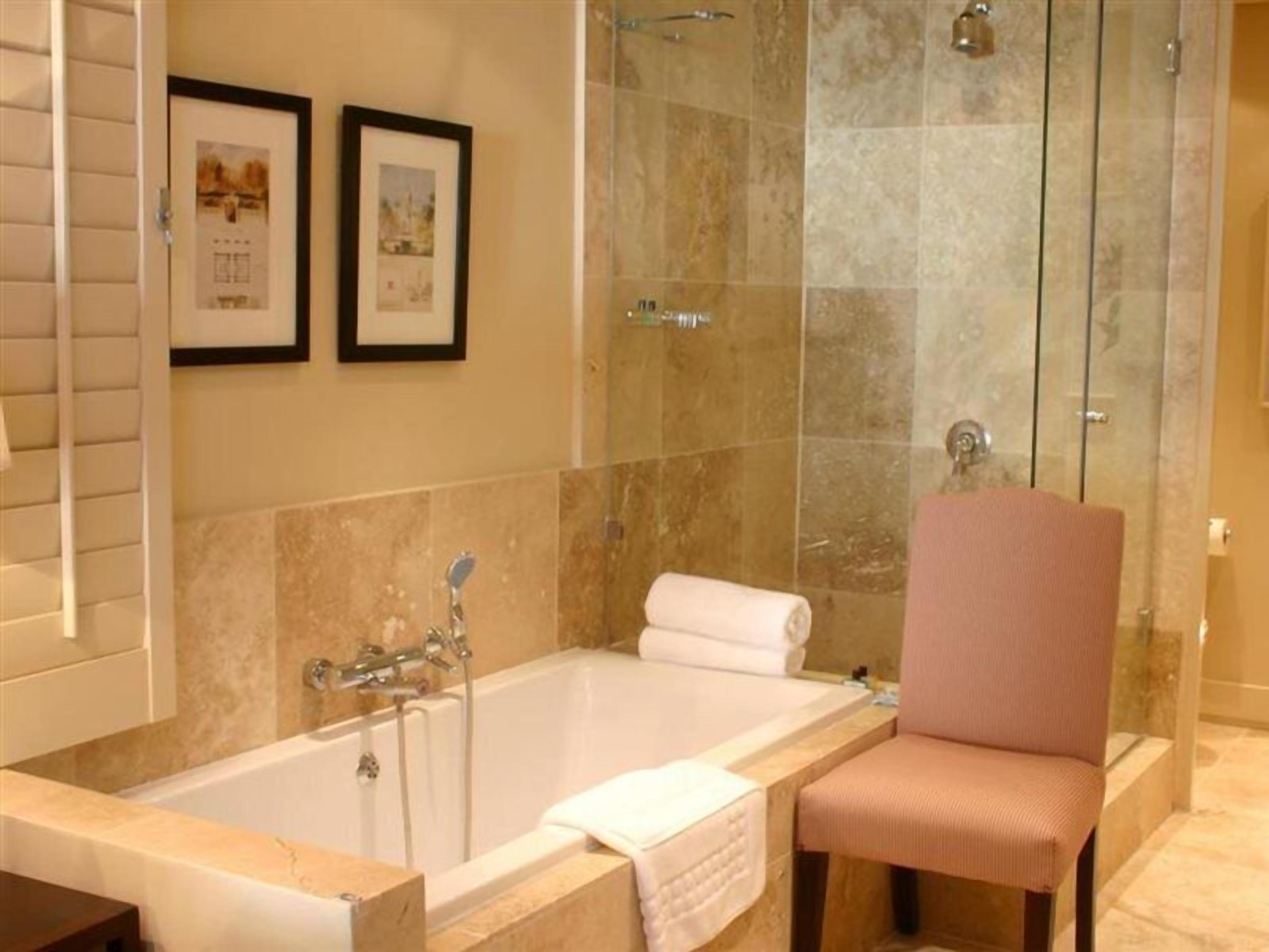 Un baño con bañera, ducha y una silla.