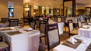 A hotel dining area with tables set for service, chairs, and a large mirror on the wall.