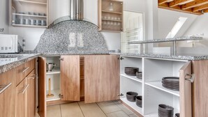 Een moderne keuken met granieten aanrechtbladen, houten keukenkastjes en een roestvrijstalen afzuigkap.