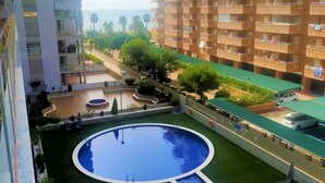 A residential building with a swimming pool, balconies, and a view of the sea.