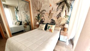 A bedroom with a large bed, a mirror, and a tropical-themed mural on the wall.