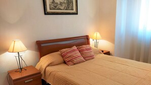 Una cama bien hecha con almohadas a rayas, un cabecero de madera y dos lámparas de noche.