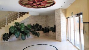 Un hall espacioso con una escalera, amplias ventanas y un diseño de techo único.