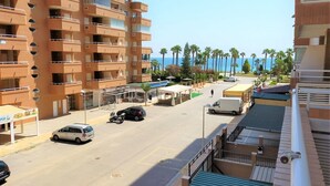 Un hotel de varios pisos con balcones, un estacionamiento techado y vista al mar.