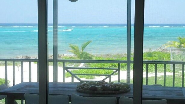 A view from a balcony overlooking the ocean with a table and chairs in the foreground. - Breathtaking view (Rum Point)
