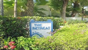 A sign for 'The Retreat at Rum Point' surrounded by lush greenery and palm trees. - Breathtaking view (Rum Point)