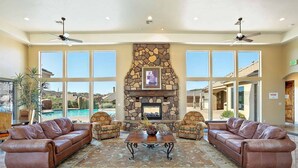 A spacious lobby with a stone fireplace, leather sofas, and large windows offering a view of a pool and landscape. - Pebble Beach Oasis by RedAwning (Washington)