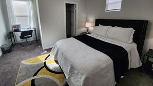 Un dormitorio con una cama, un escritorio y una silla.