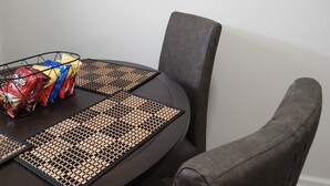 Un comedor con una mesa redonda, dos citas enmarcadas en la pared y una silla.
