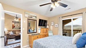 A bedroom with a bed, a TV, a wooden dresser, a ceiling fan, and a sliding glass door leading to an outdoor area. - Stunning Lake View Penthouse - Pool - Close to SDC (Branson)