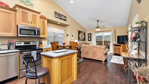 A kitchen with wooden cabinets, a microwave, and a dining area with a table and chairs. - Stunning Lake View Penthouse - Pool - Close to SDC (Branson)