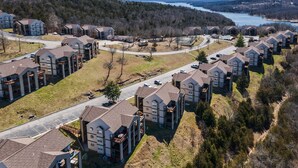 An aerial view of a residential area with multiple two-story houses, a main road, and a lake in the background. - Stunning Lake View Penthouse - Pool - Close to SDC (Branson)