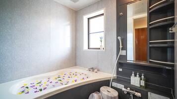 Une salle de bain moderne avec une grande baignoire, une fenêtre et un miroir.