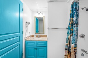 A bathroom with a turquoise door, a sink with a mirror above it, and a shower curtain with a nautical pattern. - Double balcony ocean view condo at Ocean reef resort (Myrtle Beach)