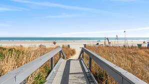 A wooden boardwalk leading to a beach with a clear sky. - Double balcony ocean view condo at Ocean reef resort (Myrtle Beach)