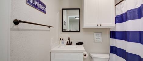 A bathroom with a toilet, sink, mirror, and a sign that reads "POOP DECK".
