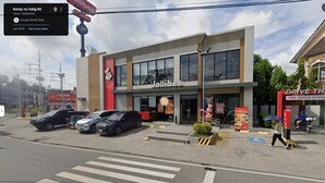 A Jollibee restaurant with a modern facade, located at a street corner with a crosswalk and parked cars. - 2-Bedroom Condo w/ Unli Wifi, Netflix, Prime Video, Apple TV, Game Console, Pool (Imus)