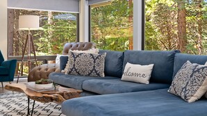 Ein modernes Wohnzimmer mit einem blauen Sofa, gemusterten Kissen, einem Holztisch und einer Lampe.