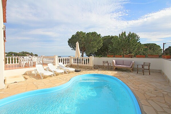 Relax by the serene pool surrounded by lush greenery and comfortable lounge chairs.