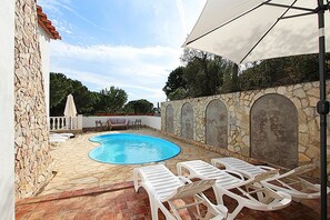 Relax by the pool surrounded by a stone wall with arched openings.
